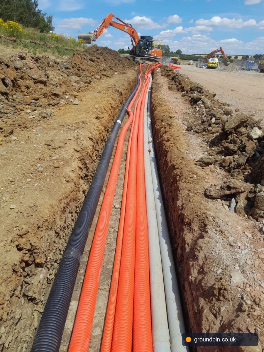 Deep trench with a stack of telecoms and utility ducts at the bottom